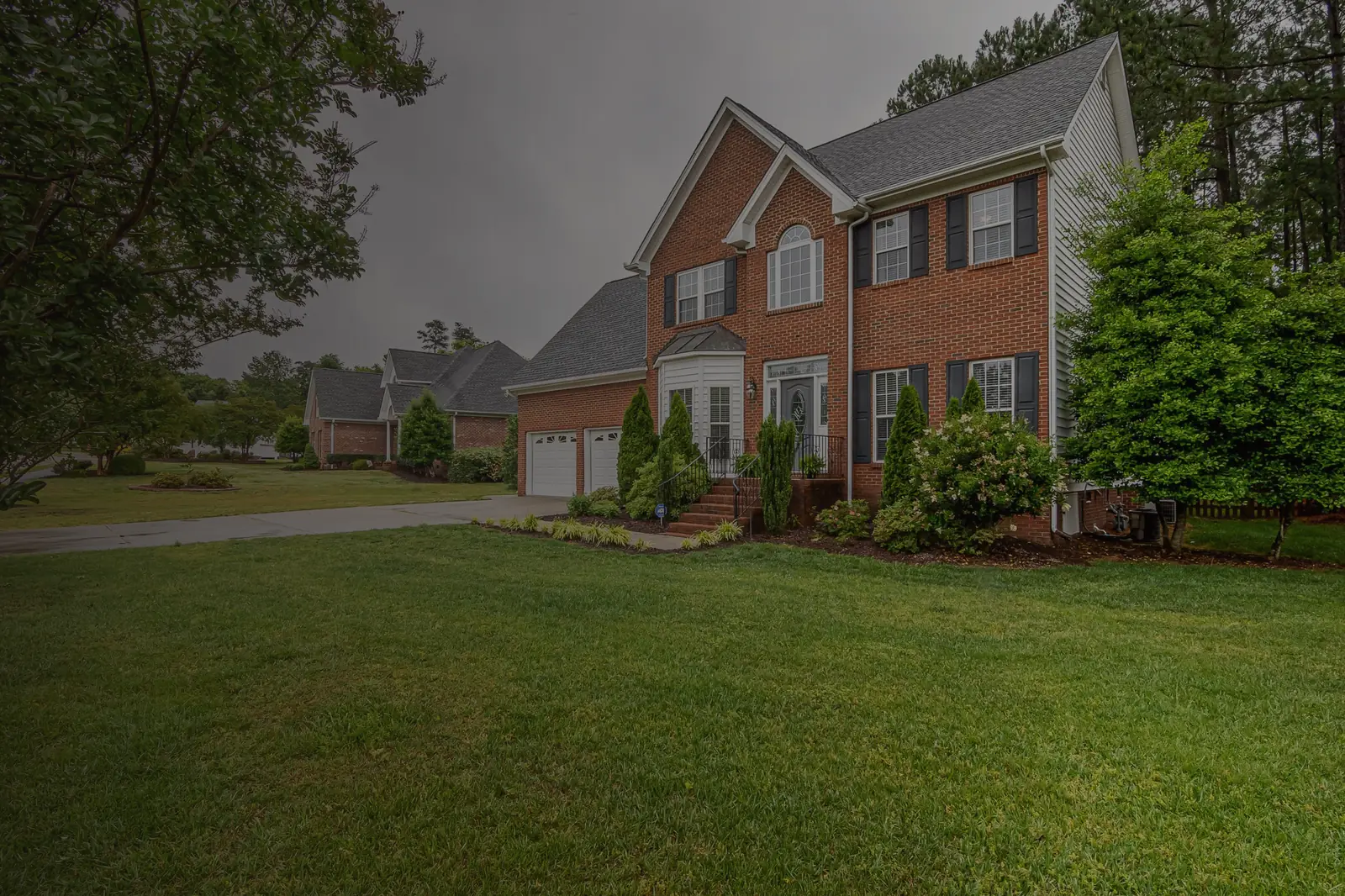 Brick two-story home among tall pine trees, illustrating a 2026 housing market guide by Peaches The Realtor